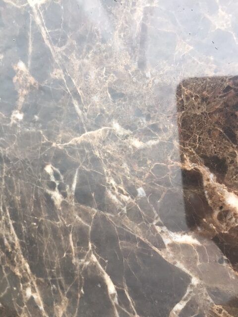 Dark brown marble with white veining. A square reflection is present on the right.