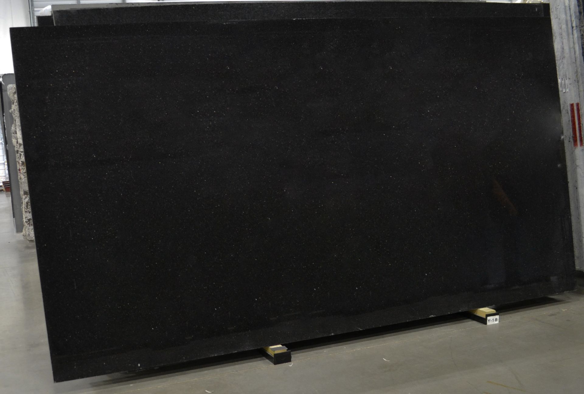 Large, dark, rectangular granite slab propped on wooden supports; likely for countertop use.