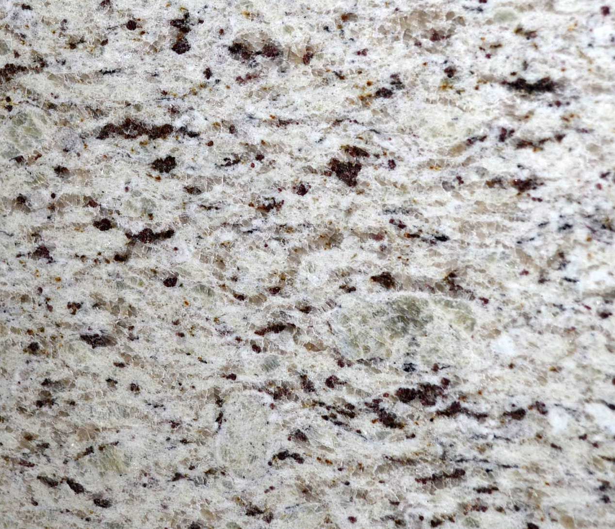 Close-up of a light-colored granite countertop with brown and black specks and swirling patterns.