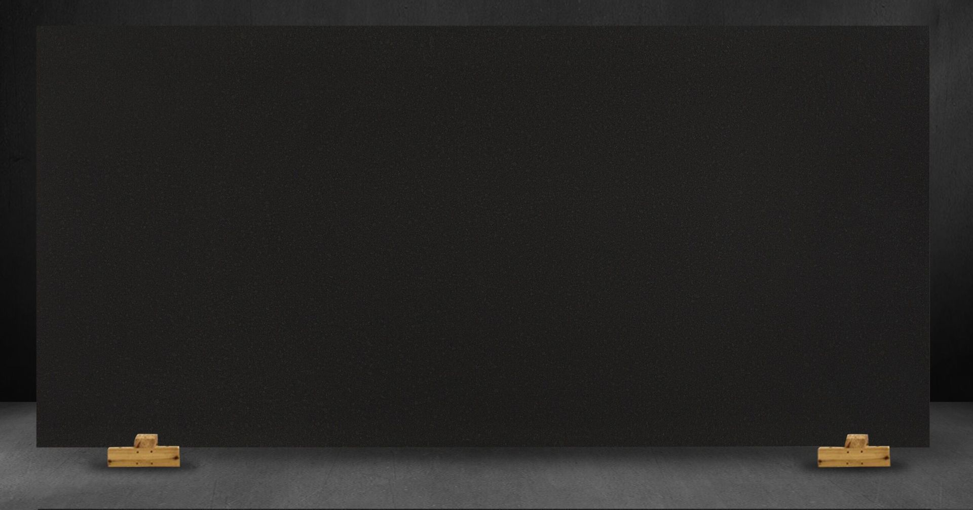 Black granite slab on display with wooden supports.