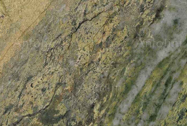 Green and yellow granite surface with cracks and variations in color.