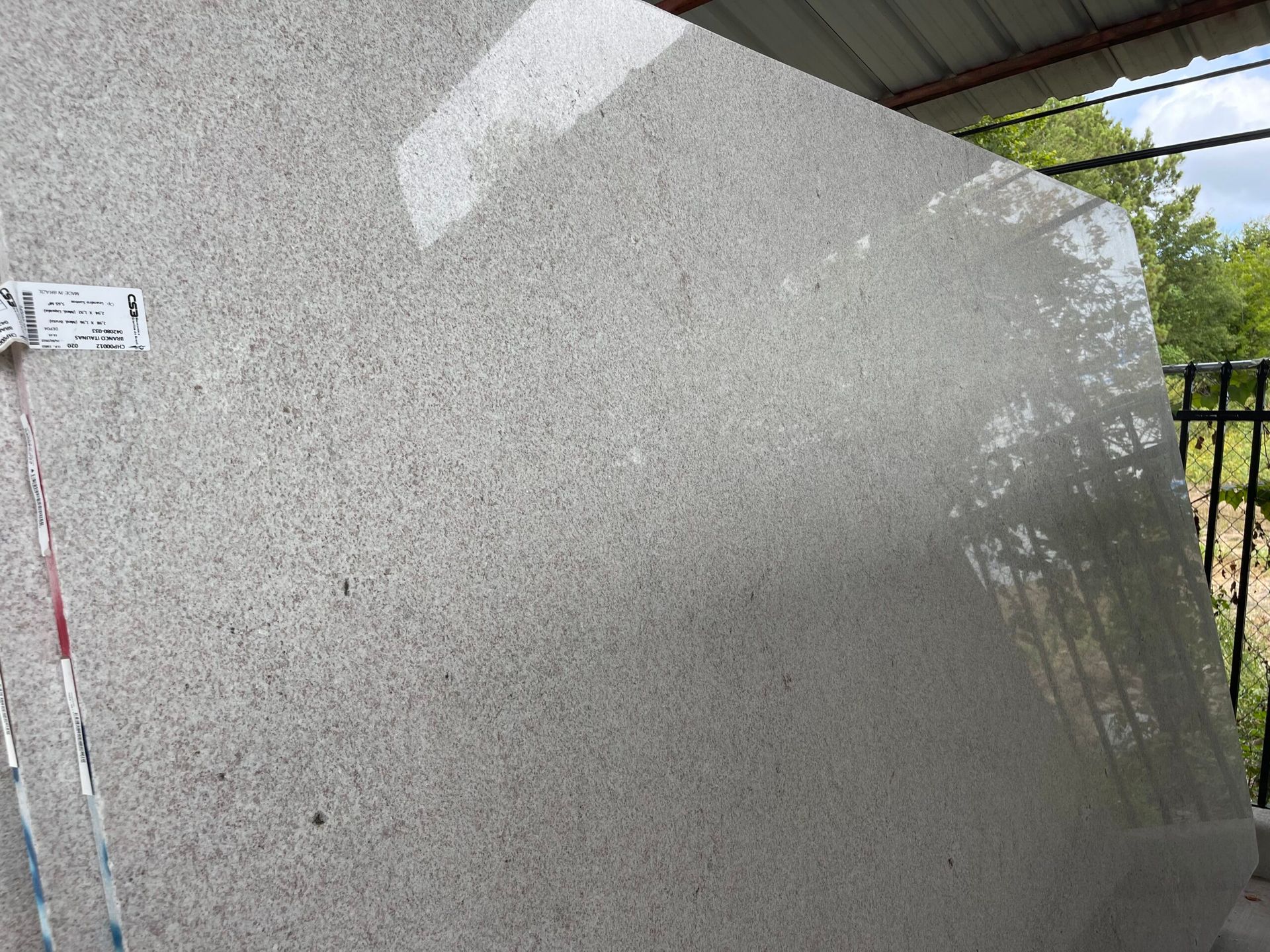 Large slab of light-colored speckled stone leaning against a structure, likely outdoors.