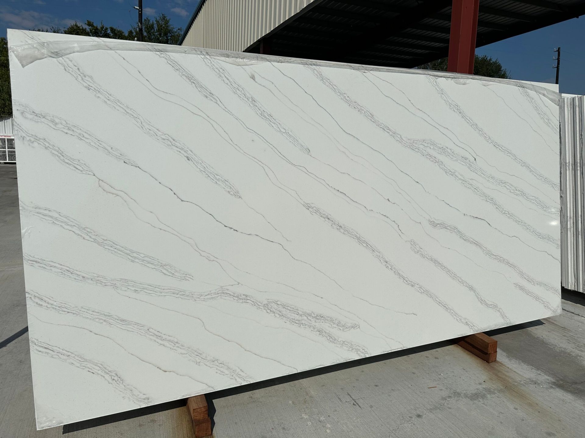 White quartz slab with gray veining, outdoors.