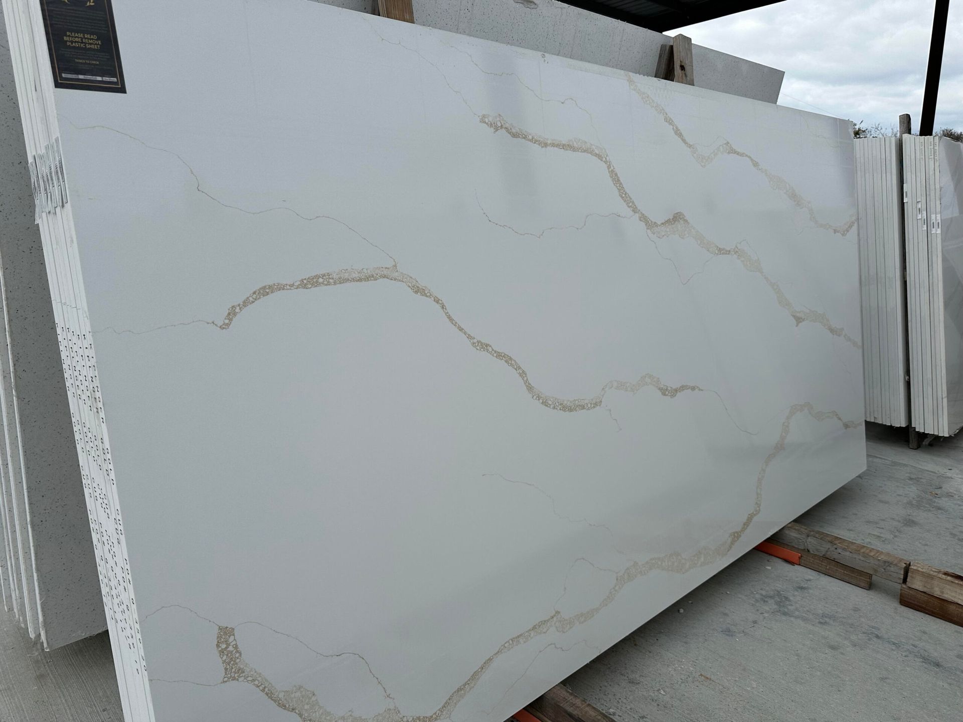 White countertop slab with gold veining, outdoors.