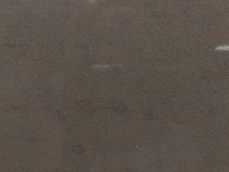 Dark gray surface with small, dark specks.