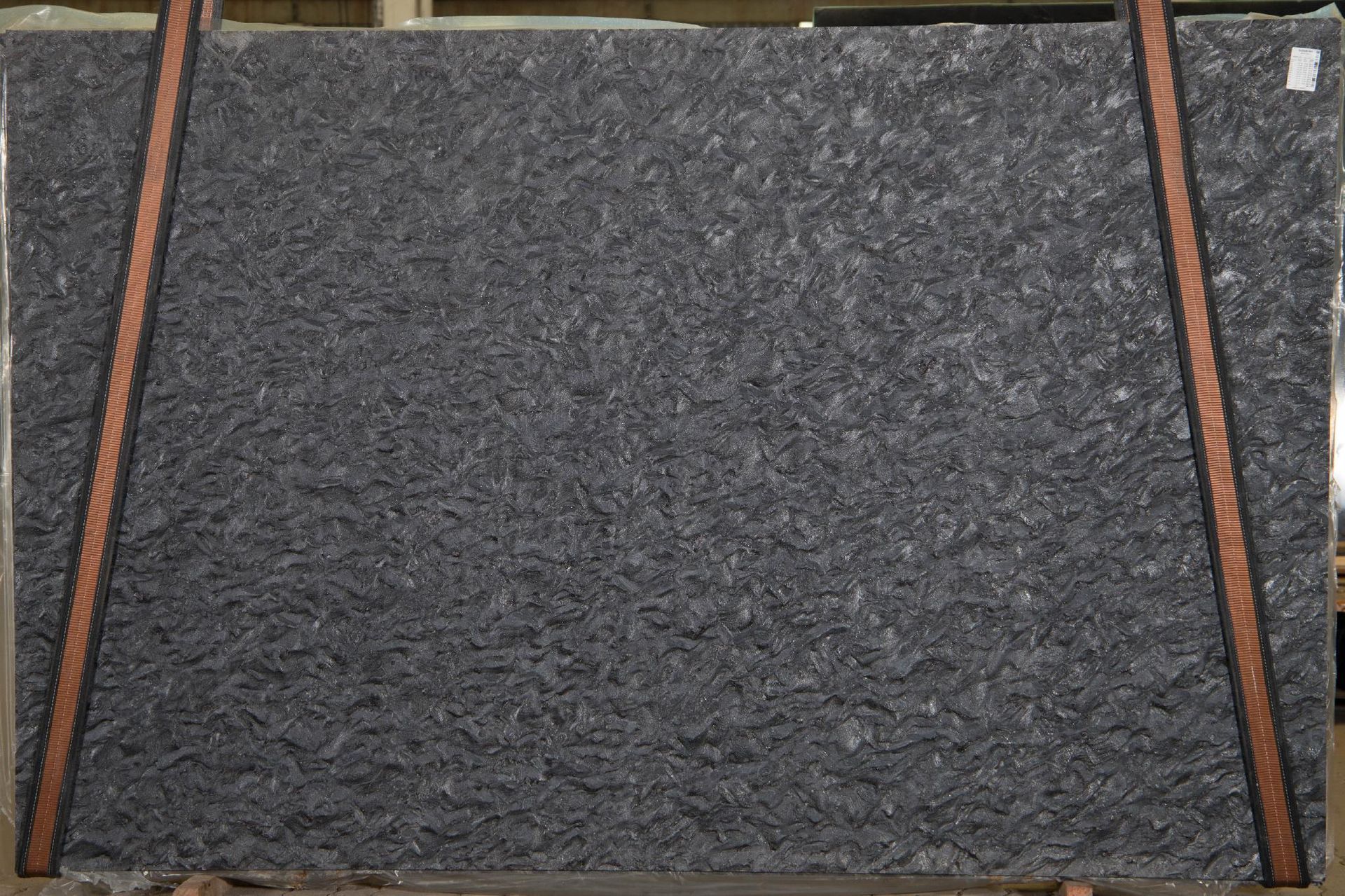 Gray granite slab with a textured surface, secured with brown straps.