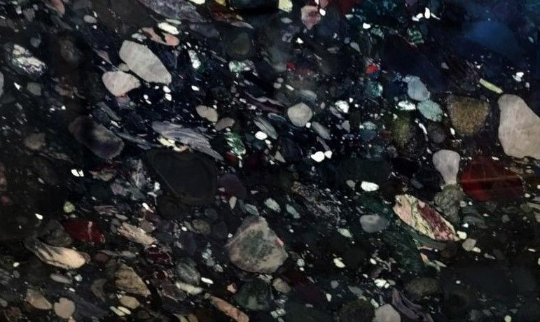 Black granite with embedded colorful stones and reflective flecks.