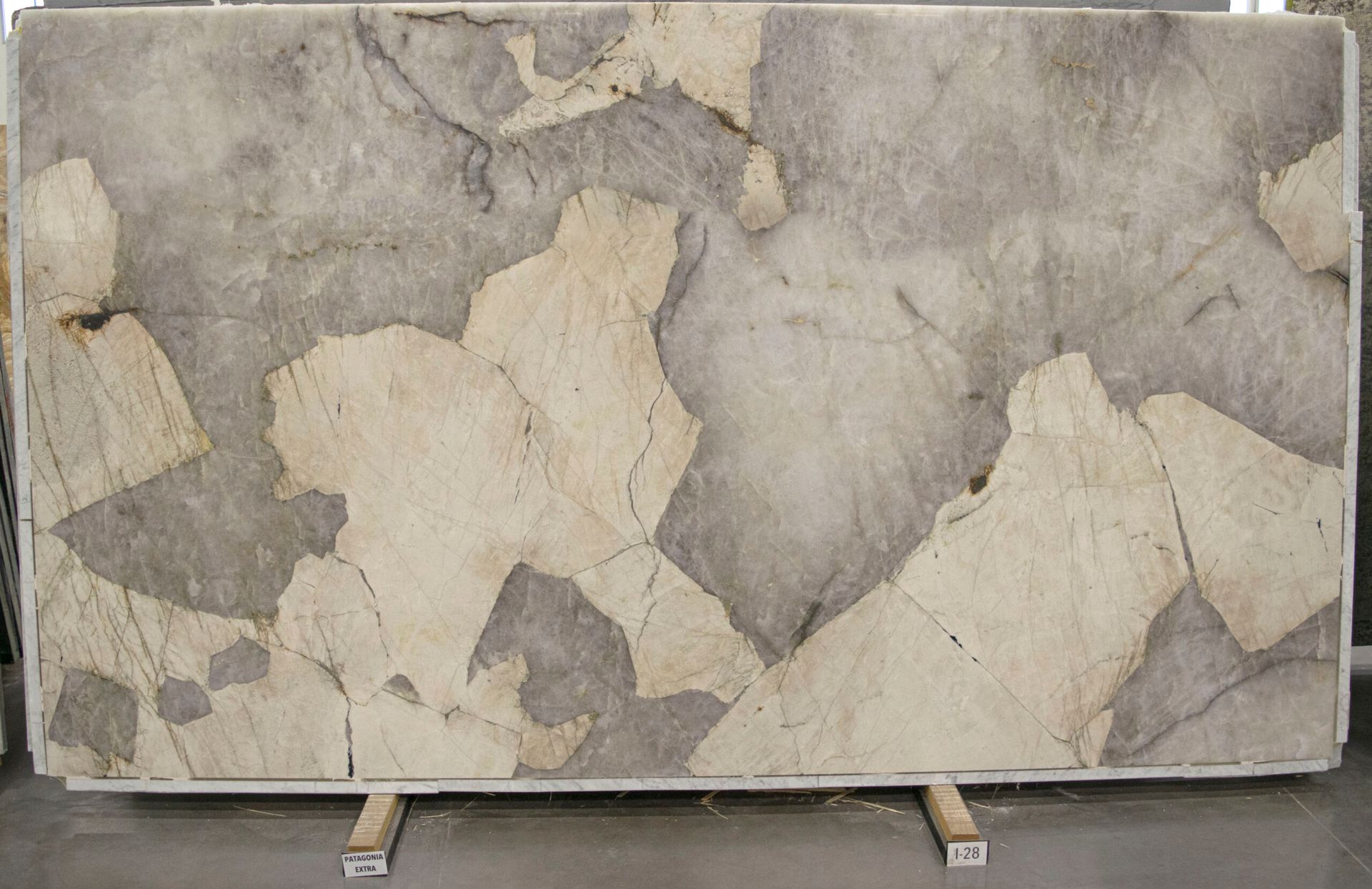Gray and beige stone slab with large irregular patches, displayed on wooden supports.