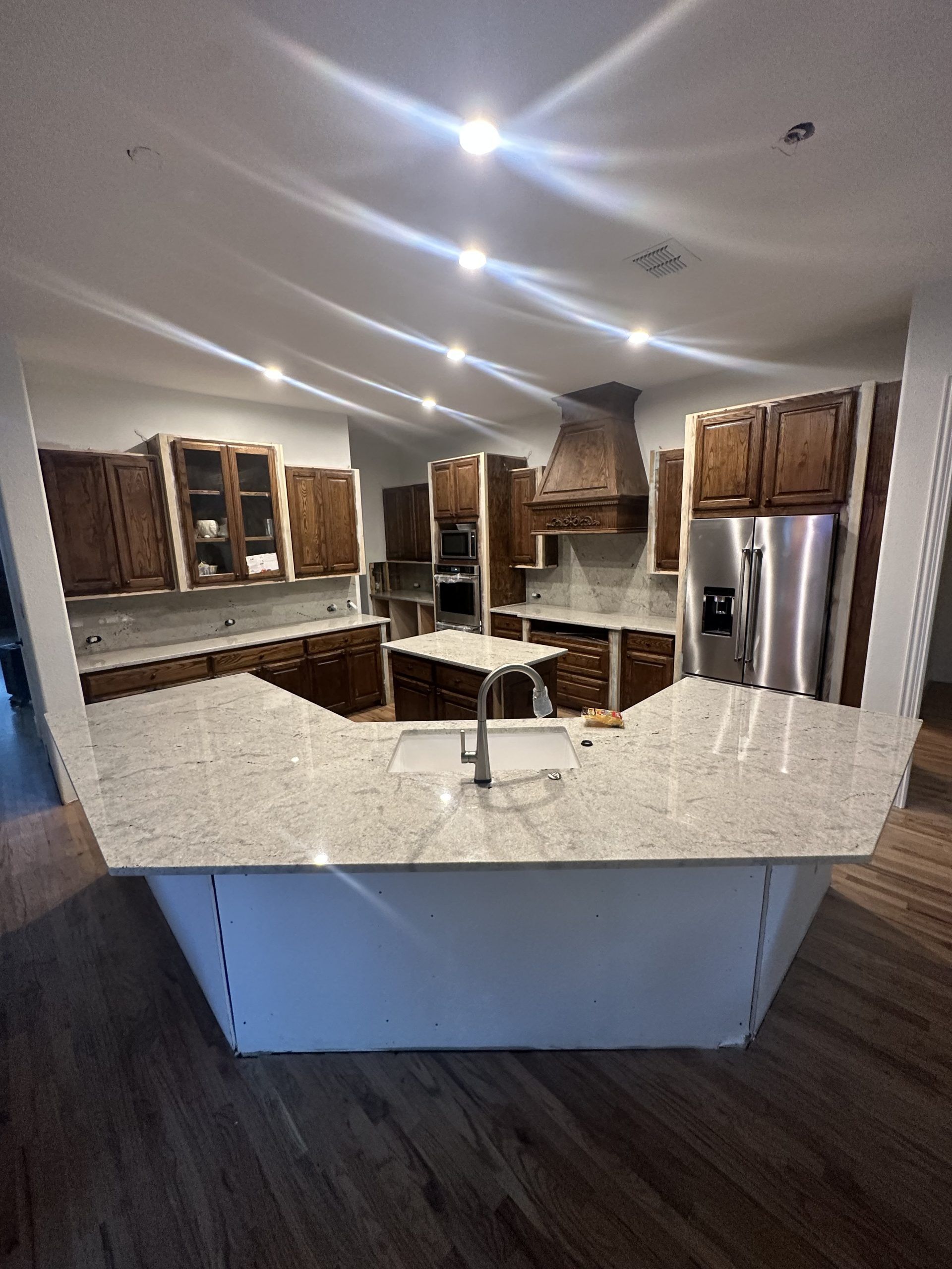 Kitchen with light-colored countertops, brown cabinets, stainless steel appliances, and white island.