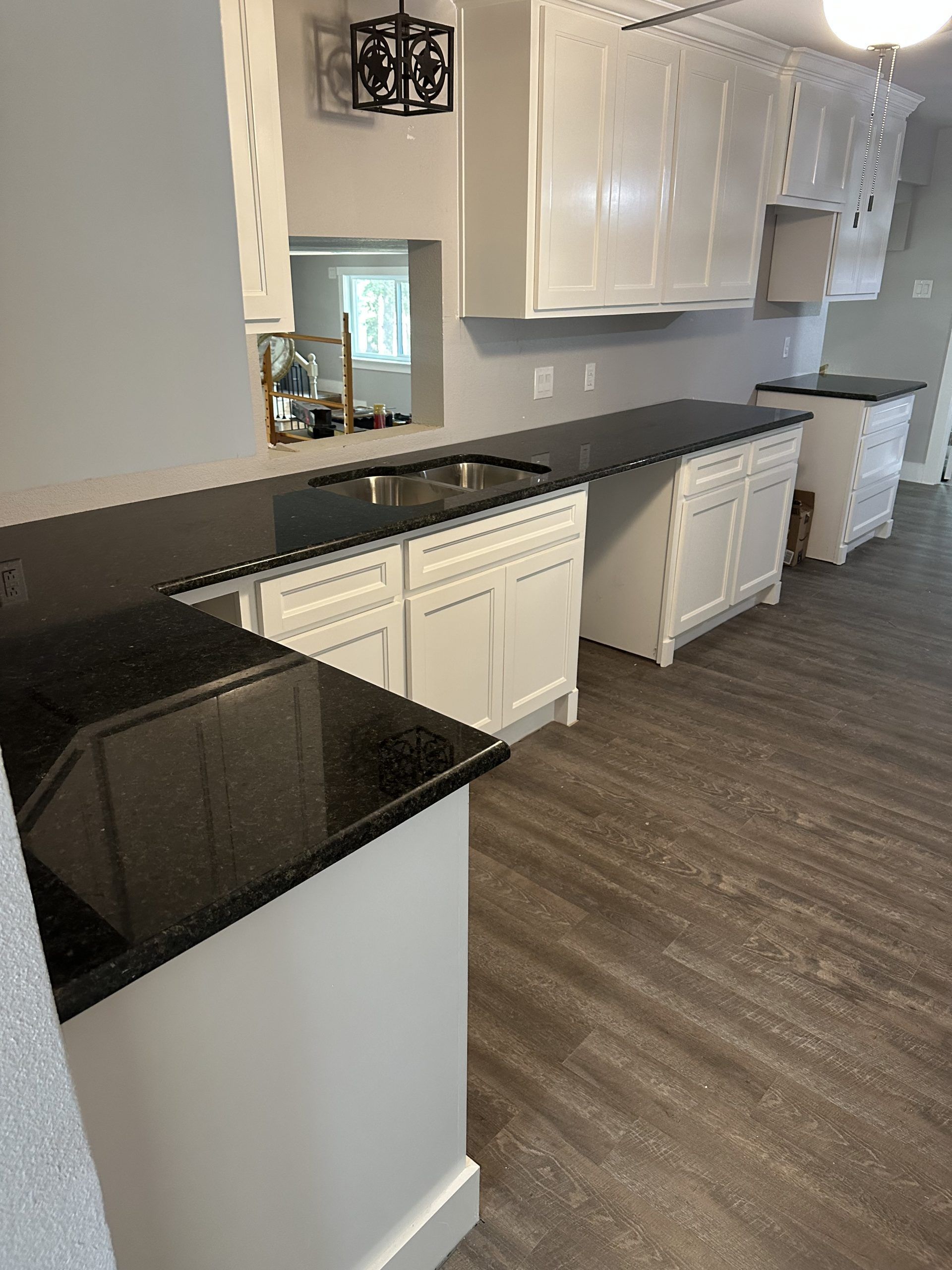White kitchen cabinets with black countertops and gray flooring.