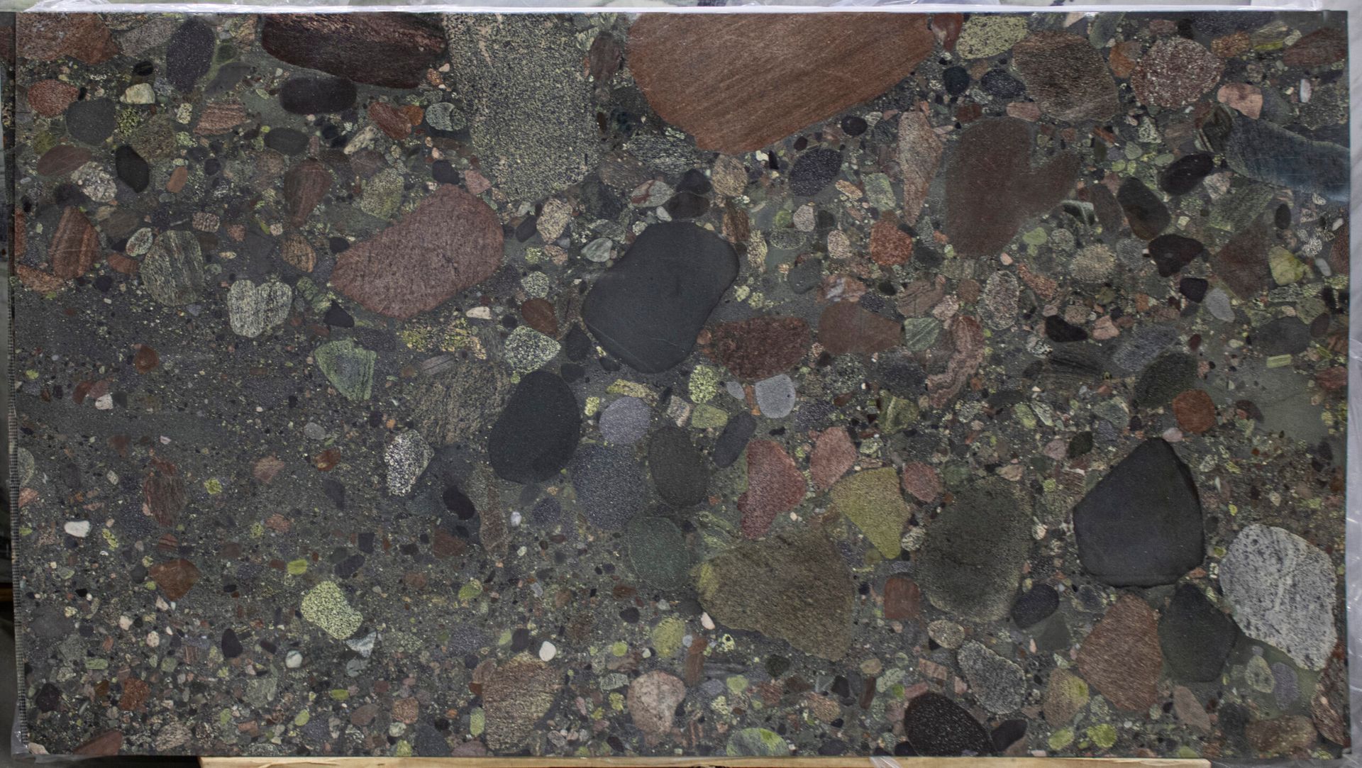 Close-up of dark speckled stone surface with embedded colorful pebbles and stones.