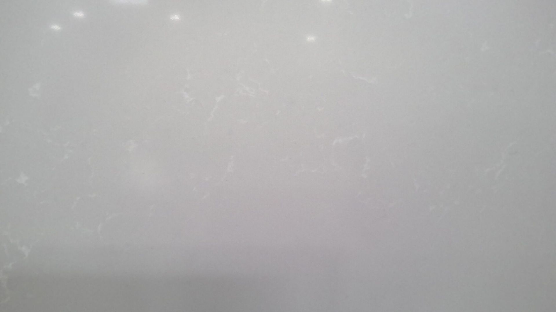 White surface with faint, irregular imperfections and light reflection.