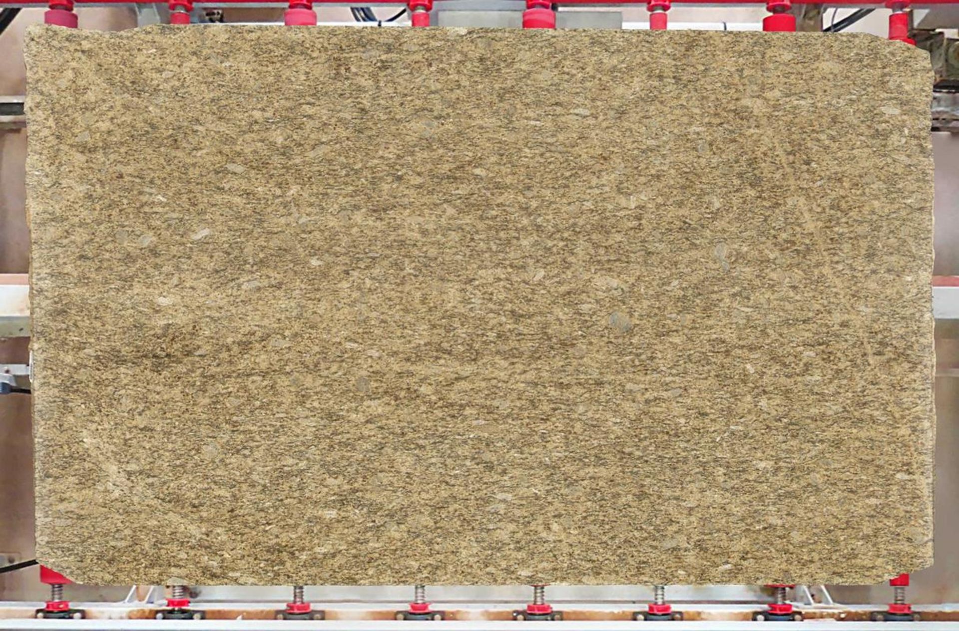 A rectangular board of light brown compressed material, possibly insulation, held by a machine.