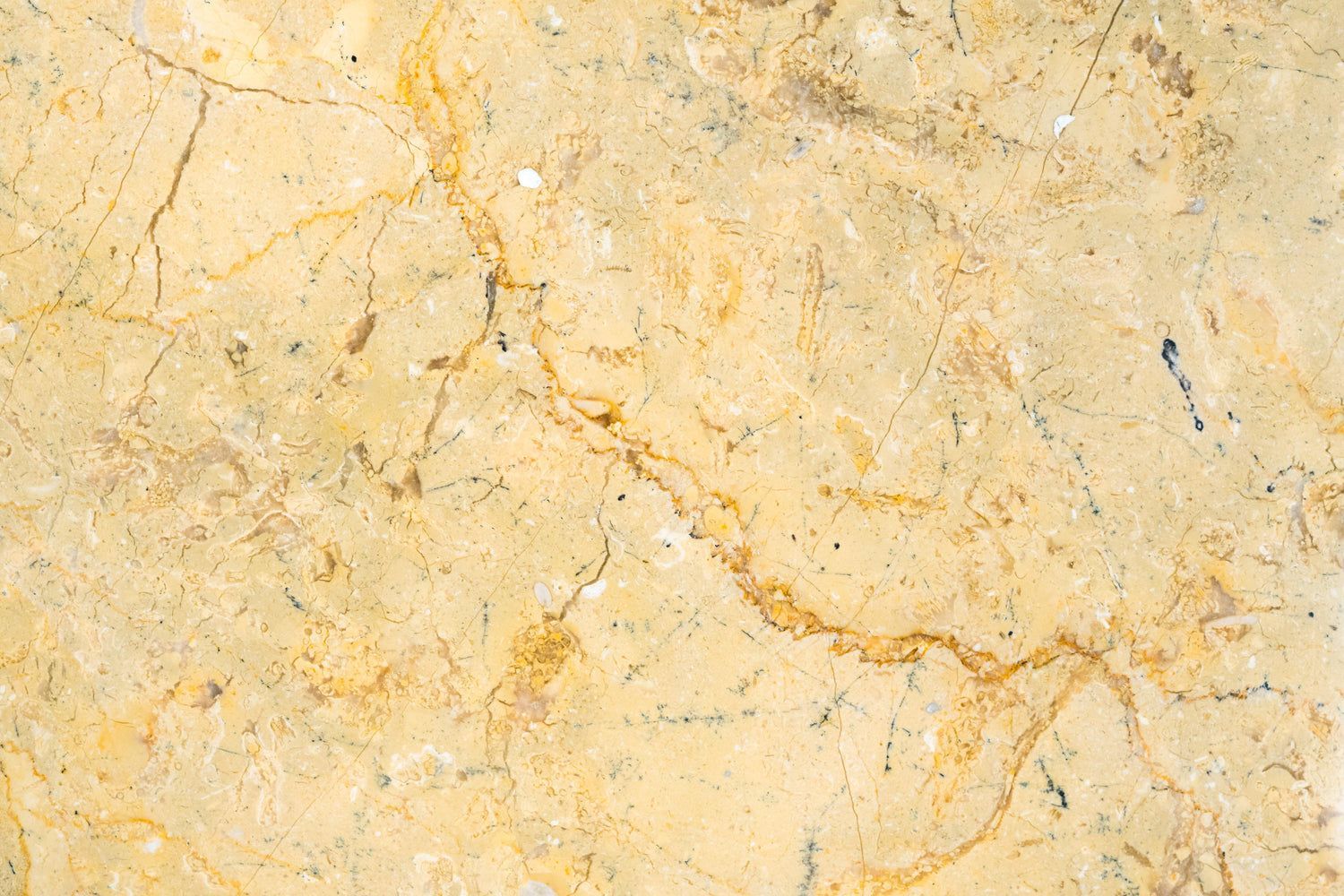 Yellow marble surface with brown veins and cracks.