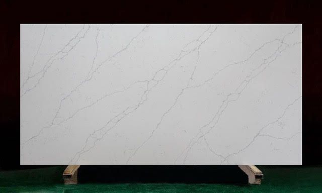 White countertop slab with subtle veining, displayed on wooden supports.
