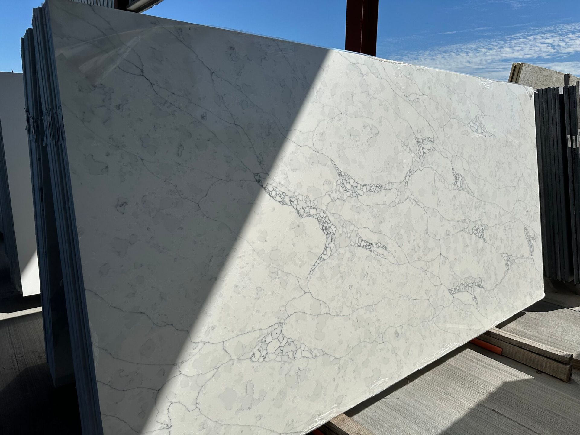 Large white marble slab with grey veining, stacked outdoors.