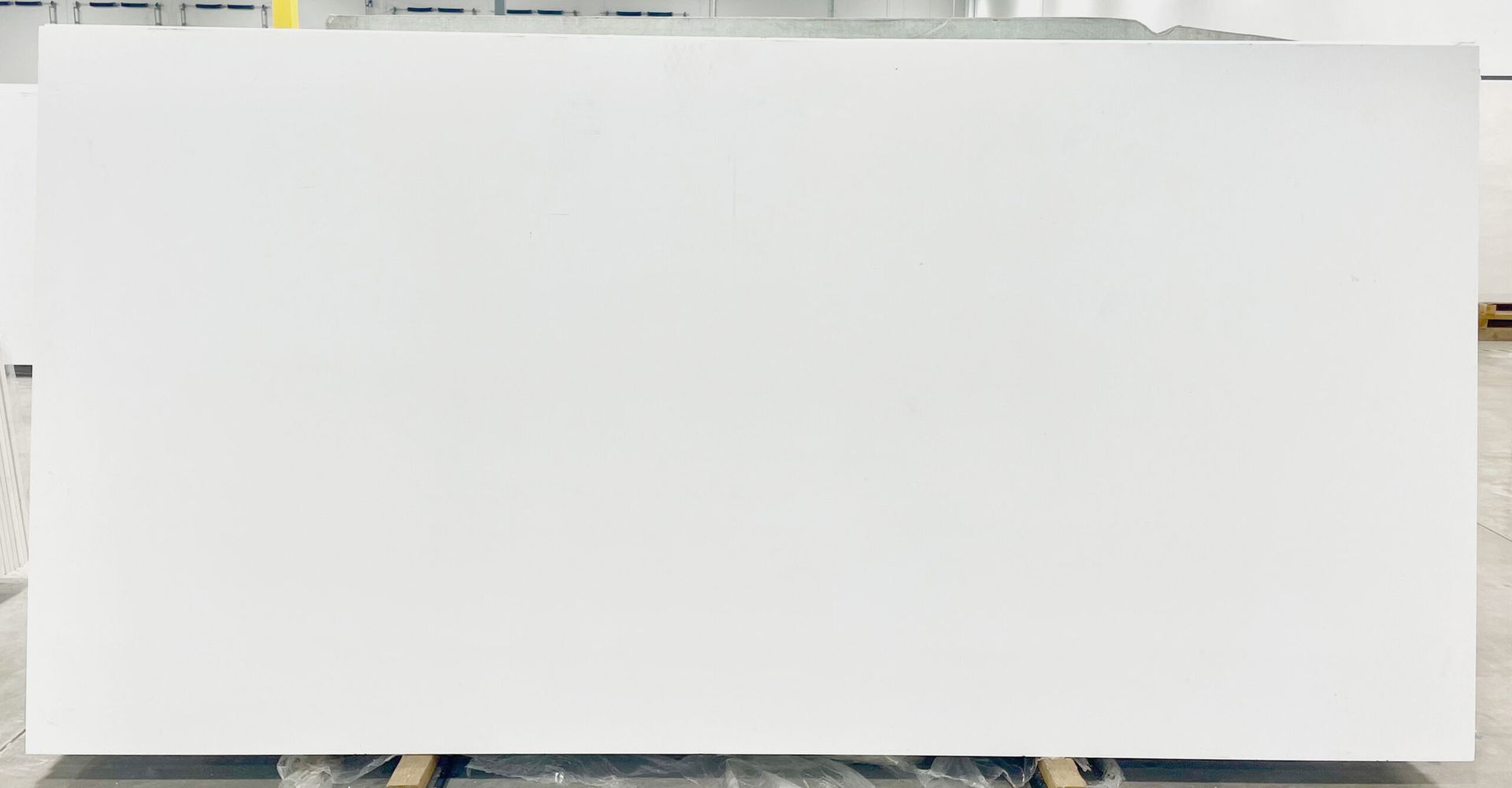 Large, rectangular, white slab of stone or quartz in a warehouse setting.