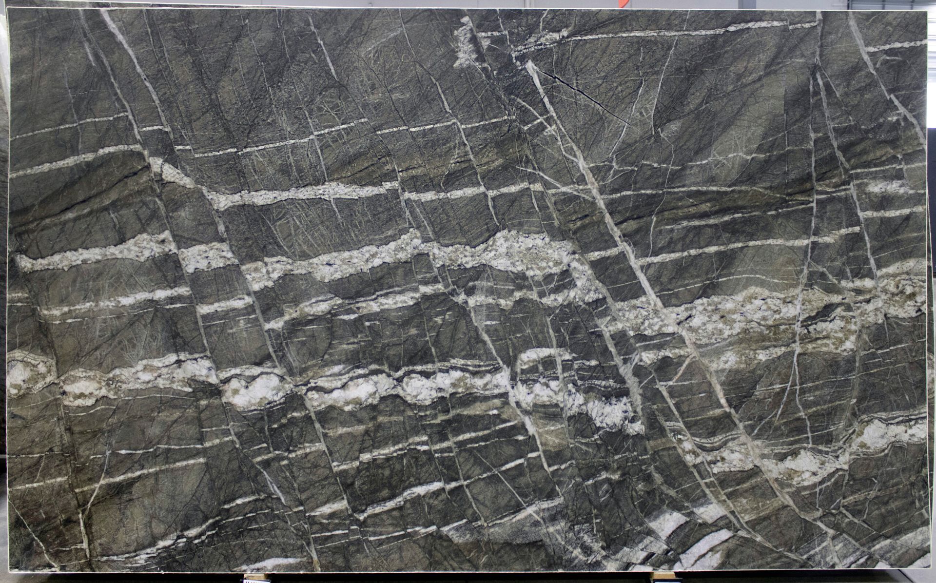 Dark gray granite slab with white veins and striations.