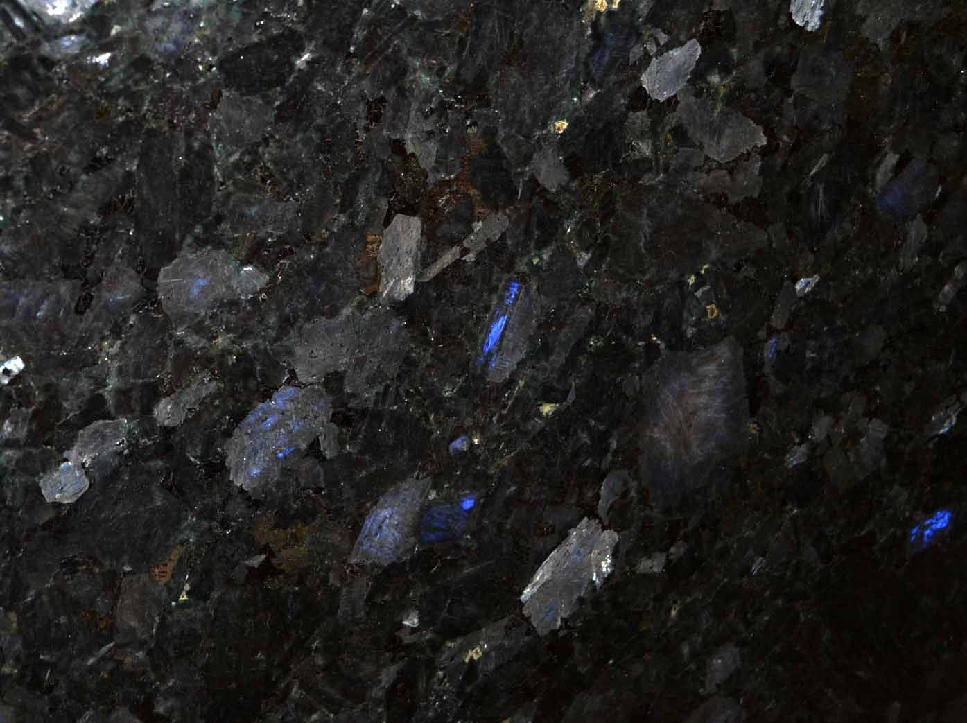 Dark stone surface with blue and silver crystalline inclusions.