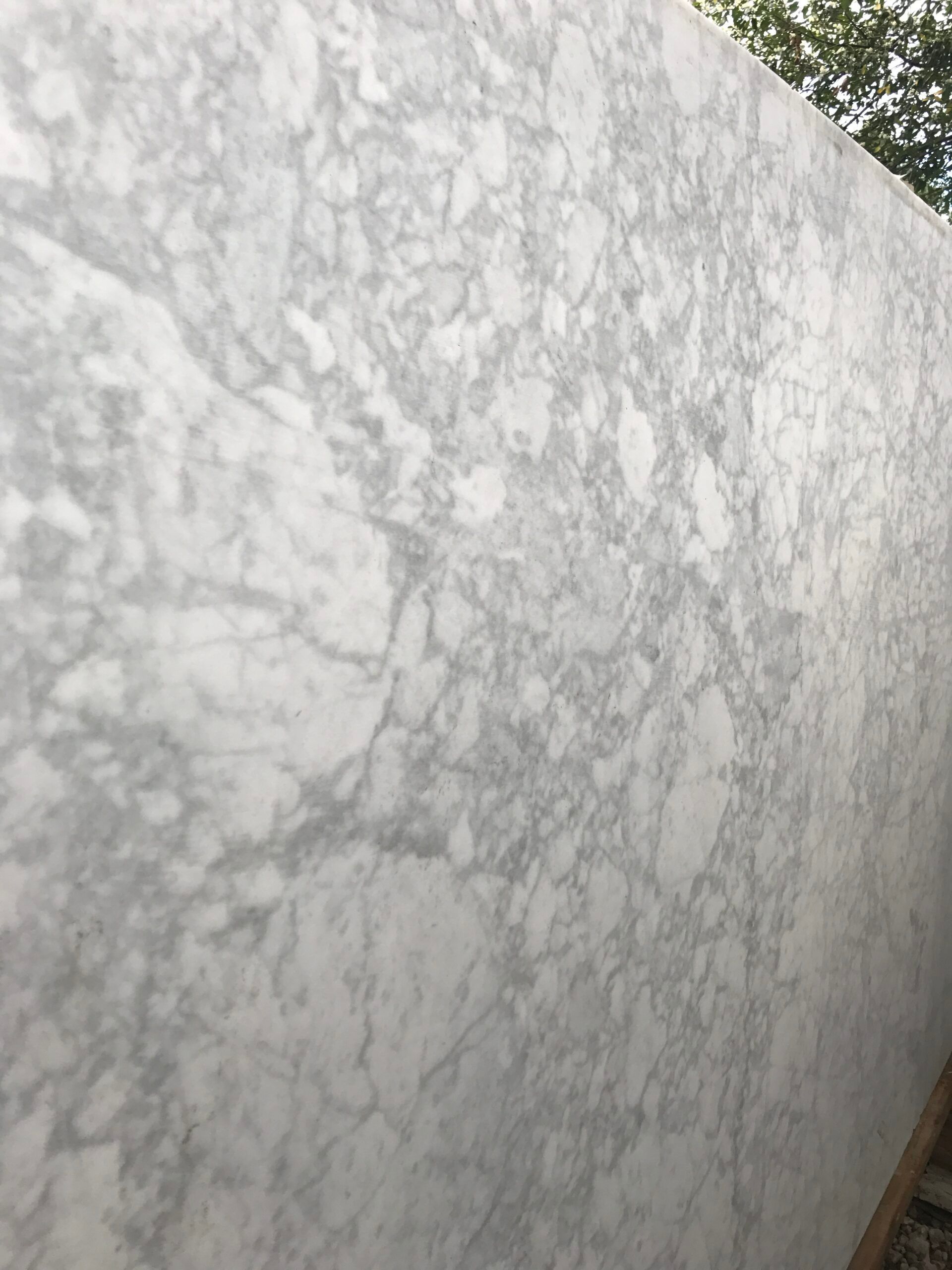Gray and white marble slab with veining, leaning against a wall.