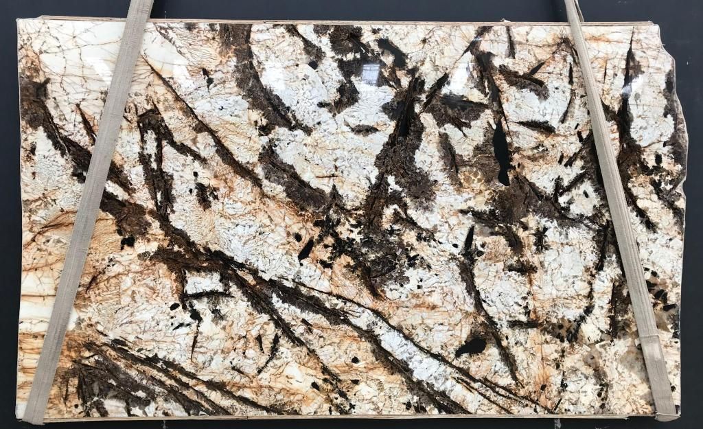 White and brown granite countertop slab with dark veining, secured with two gray straps.