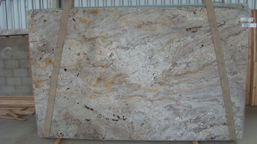 Granite slab, light beige and brown with dark flecks, secured with straps in a warehouse.