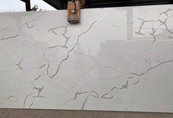 White quartz slab with gray veining, under a metal overhang.