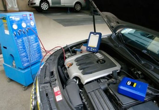 Una macchina diagnostica e uno scanner portatile collegati al motore di un'Audi all'interno di un'officina meccanica.