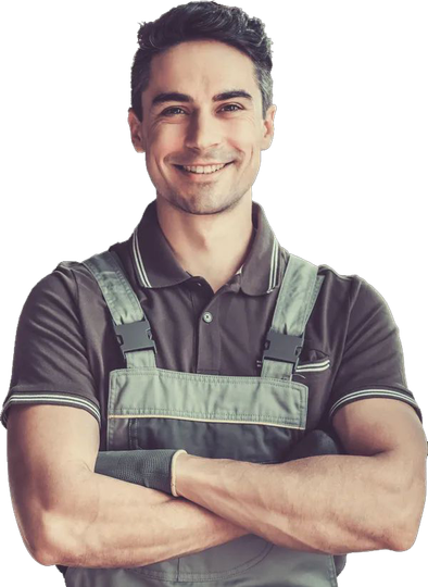 Una persona sorridente con una polo marrone e una tuta da lavoro verde, in piedi con le braccia incrociate.