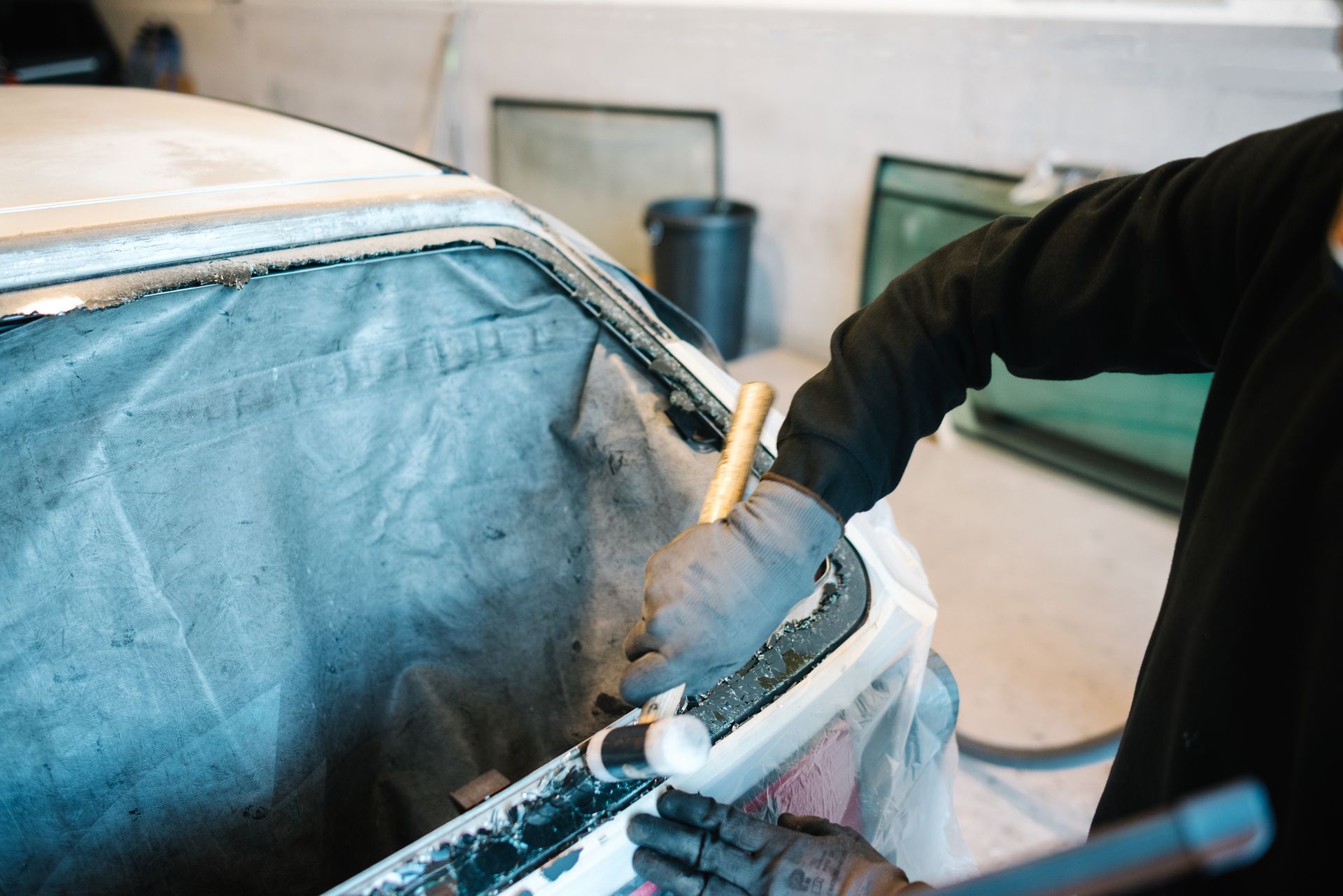 A man is working on a car windshield in a garage.