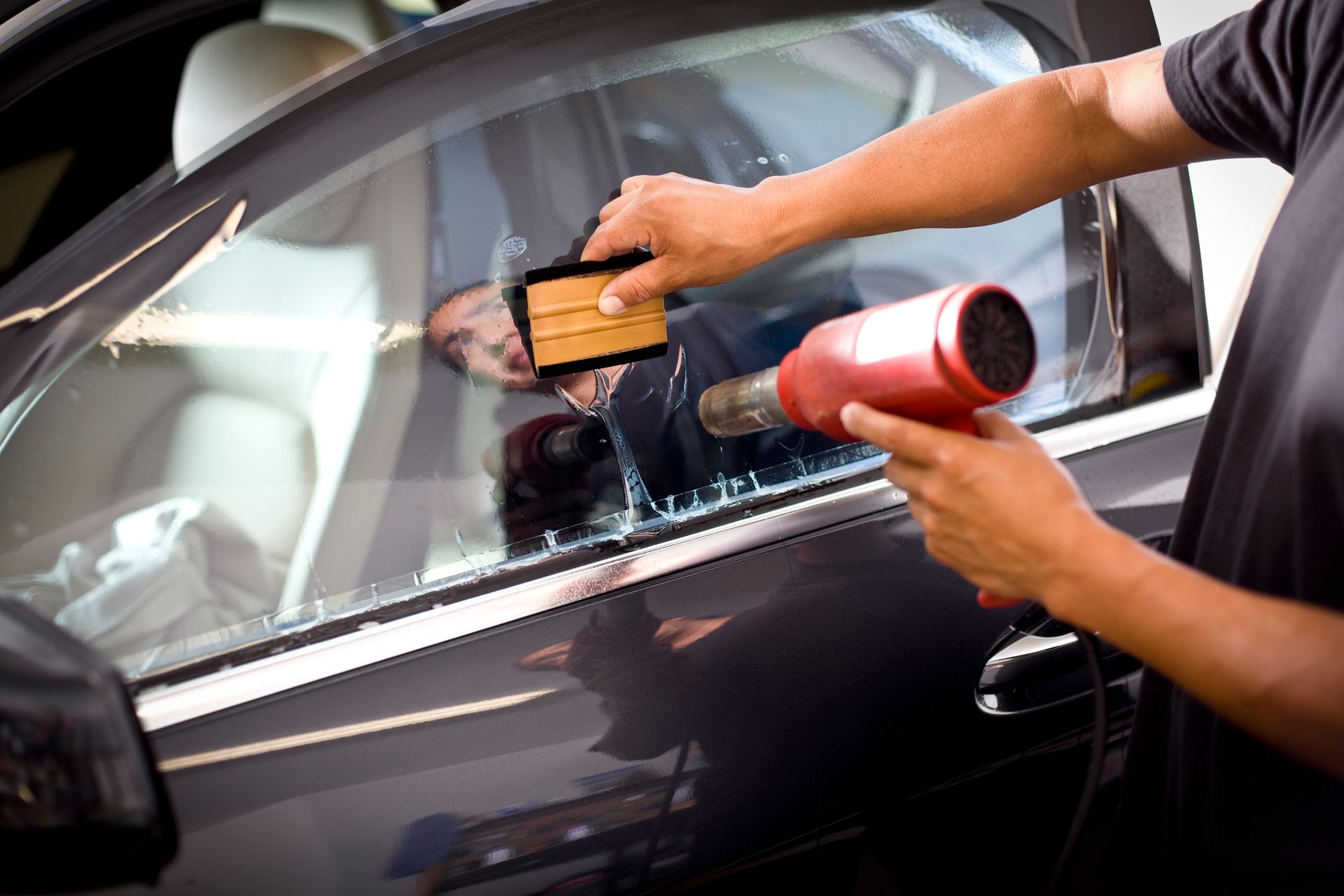 A man is applying window tinting to a car window.