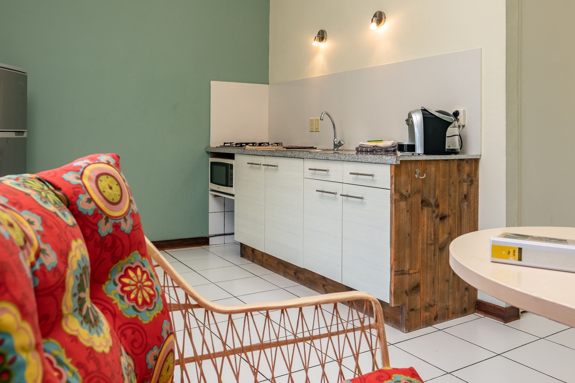 Small kitchen with white cabinets, stainless steel appliances, and wood paneling.
