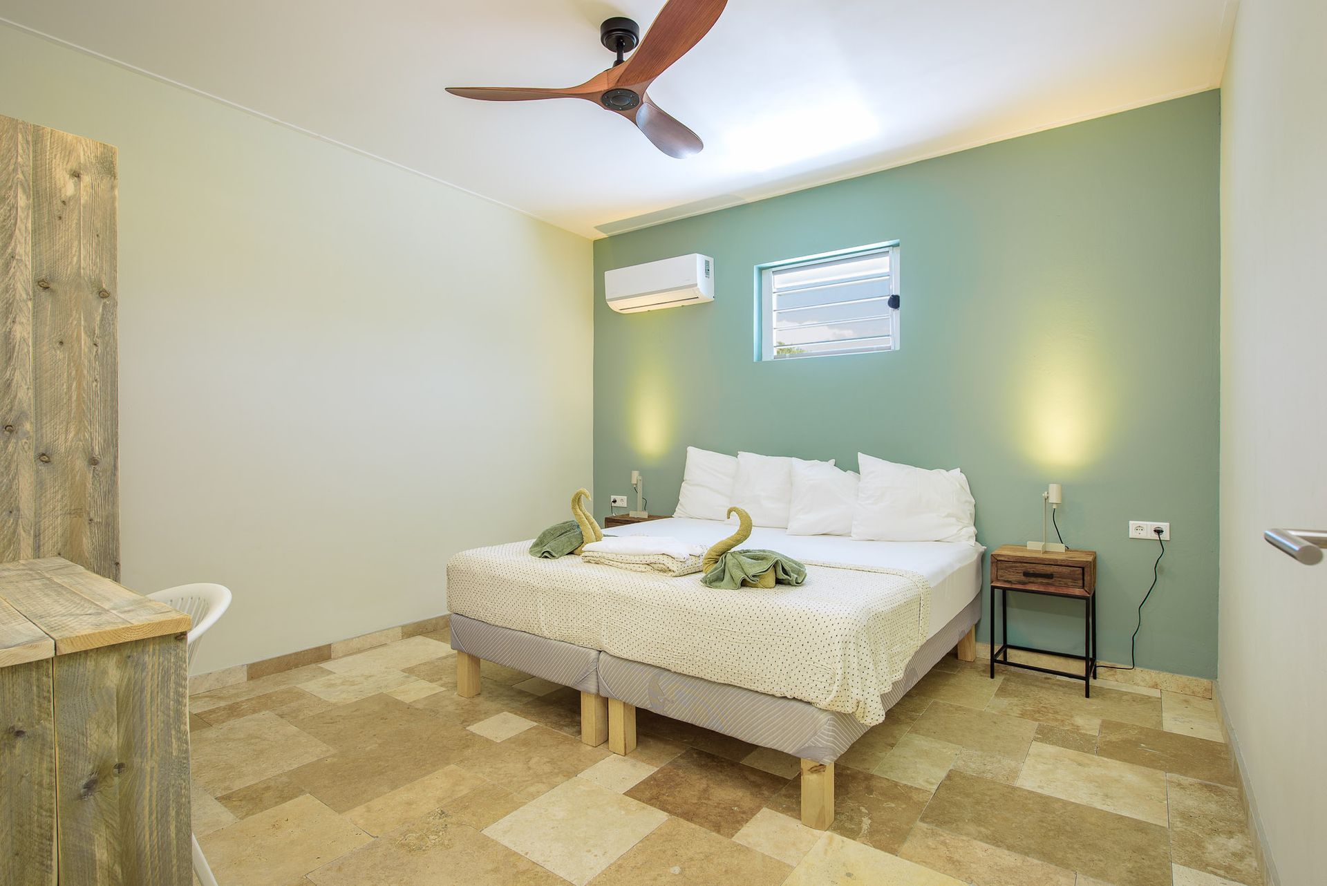 Bedroom with a bed, nightstand, and ceiling fan. Green accent wall, light-colored flooring.