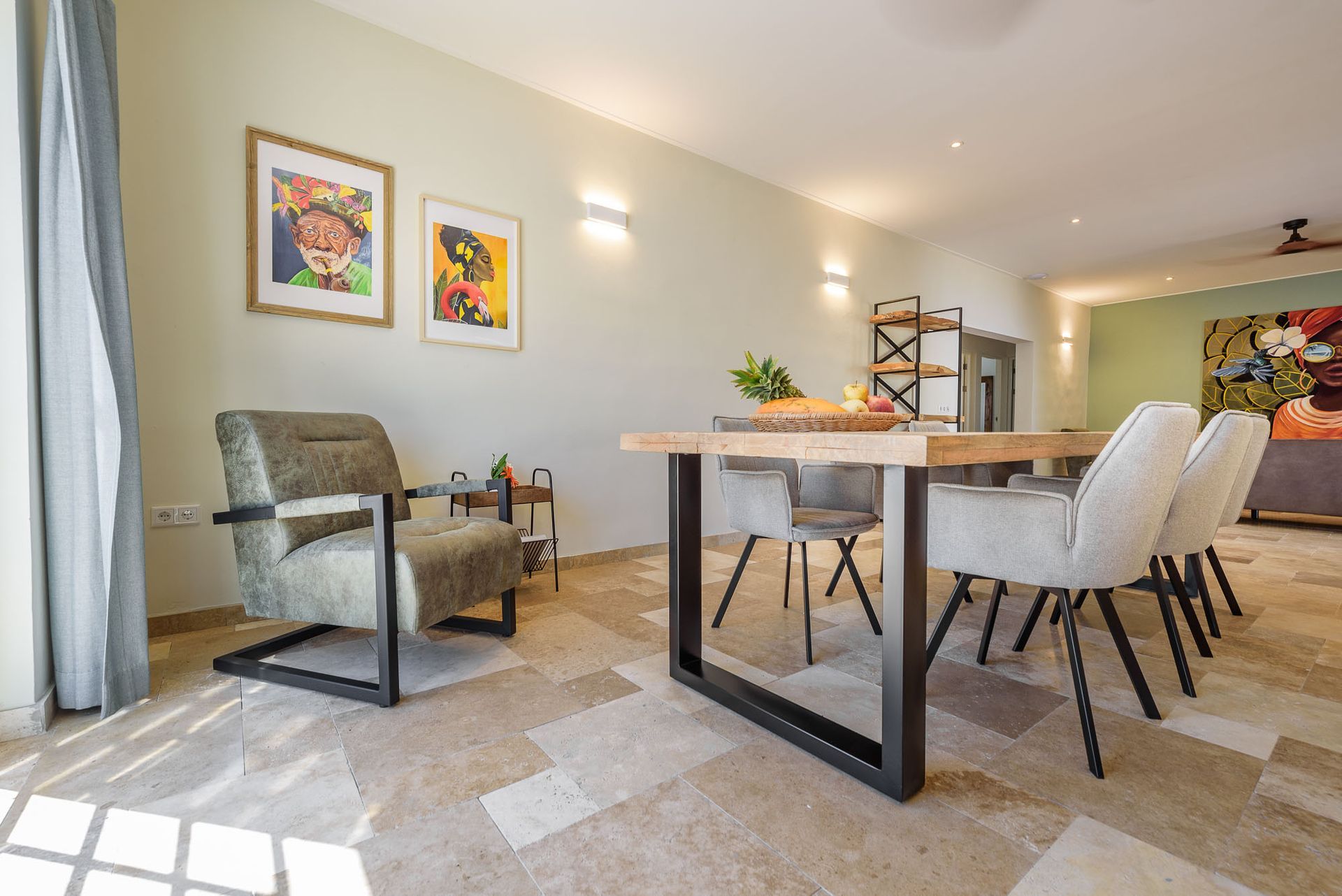 Dining room: light walls, wood table with chairs, armchair, art, and tiled floor.