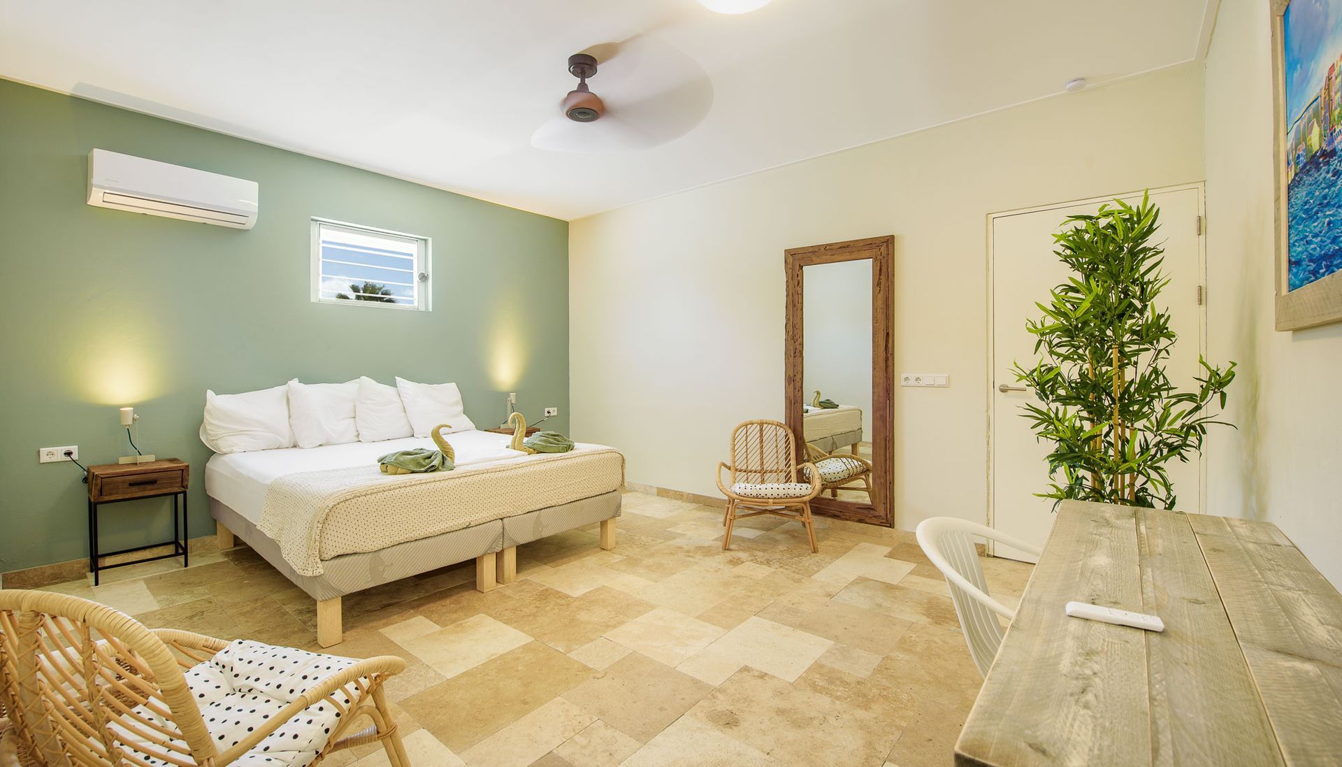 Bedroom with a bed, chairs, mirror, and a small table on a stone floor.