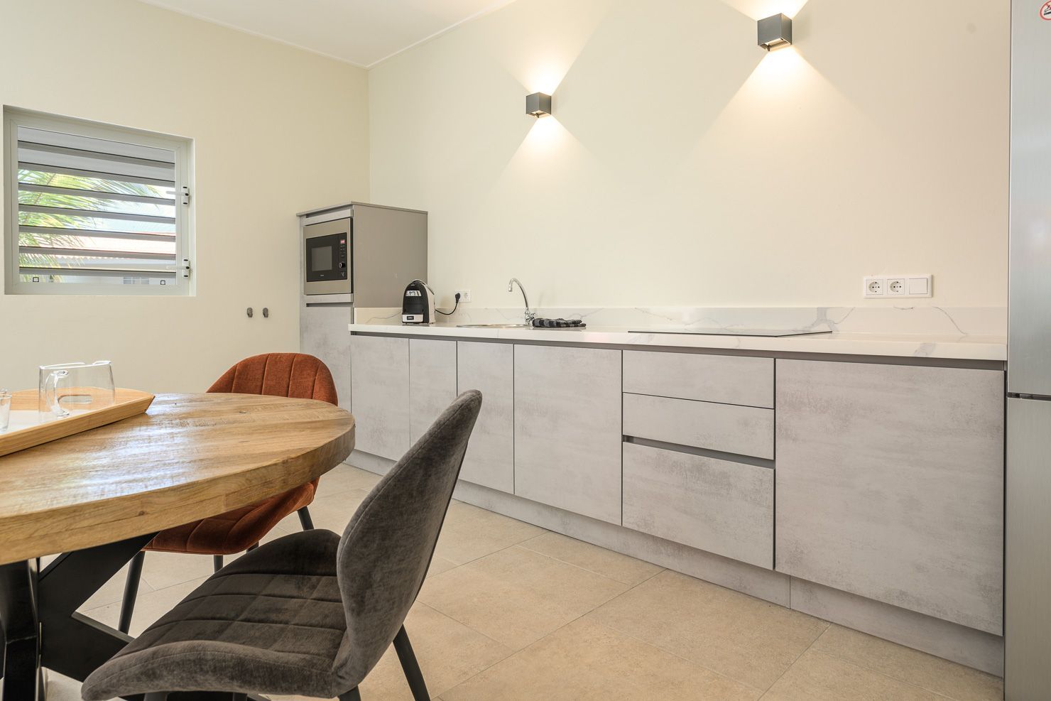Modern kitchen with light gray cabinets, a round wooden table, and a built-in oven.