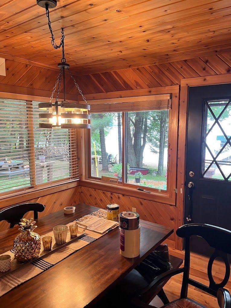 A dining room with a wooden table and chairs and a large window.