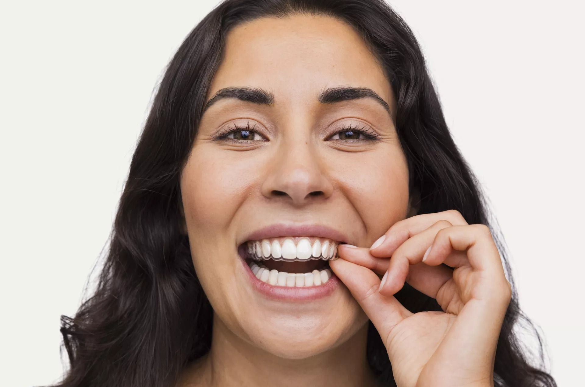 Smiling person removing floss from their teeth against a white background