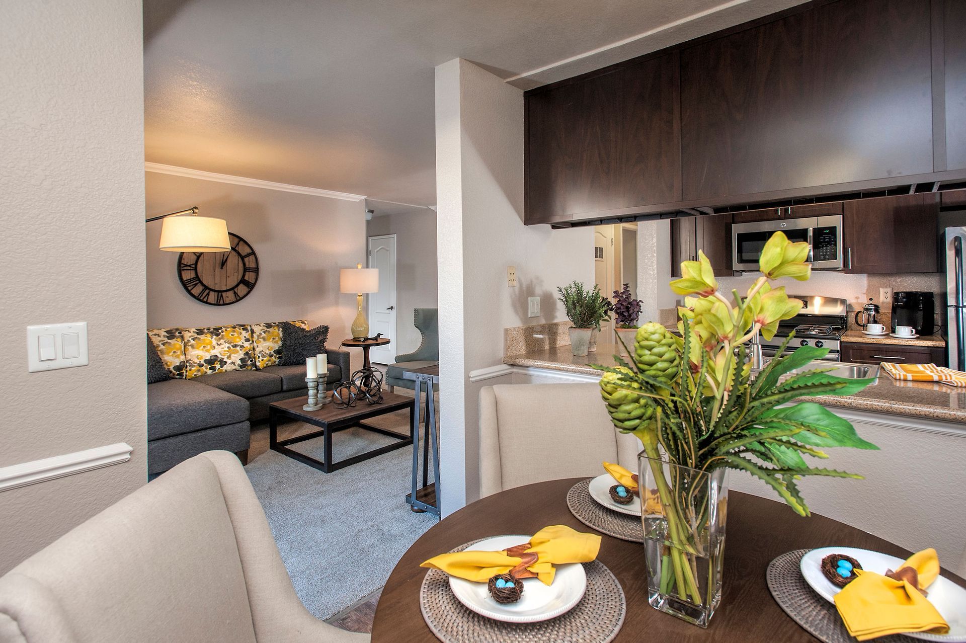 Open-concept living area with dining table, kitchen, and gray sofa.