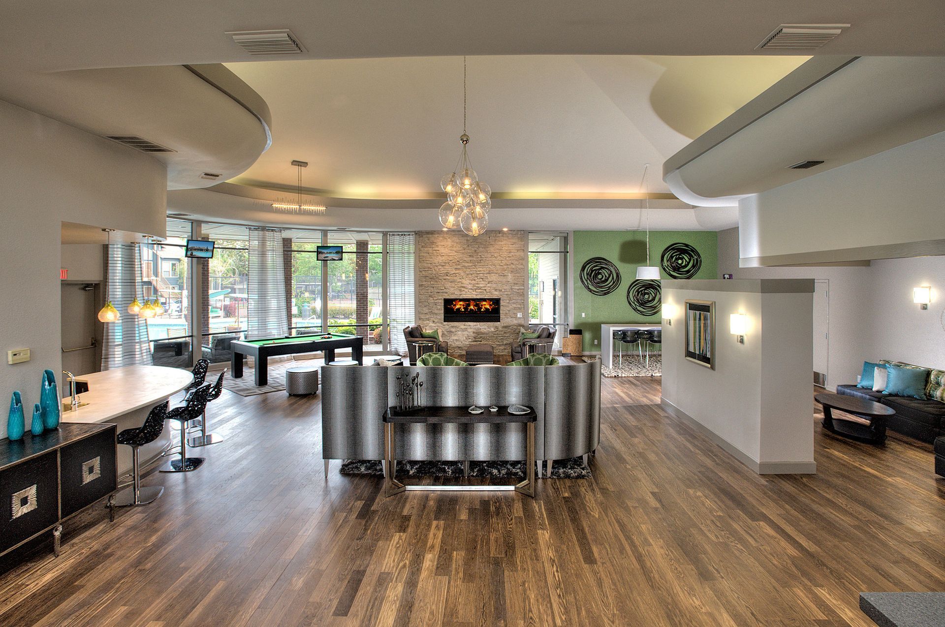 Contemporary apartment community lobby with curved reception desk, seating, and a fireplace.