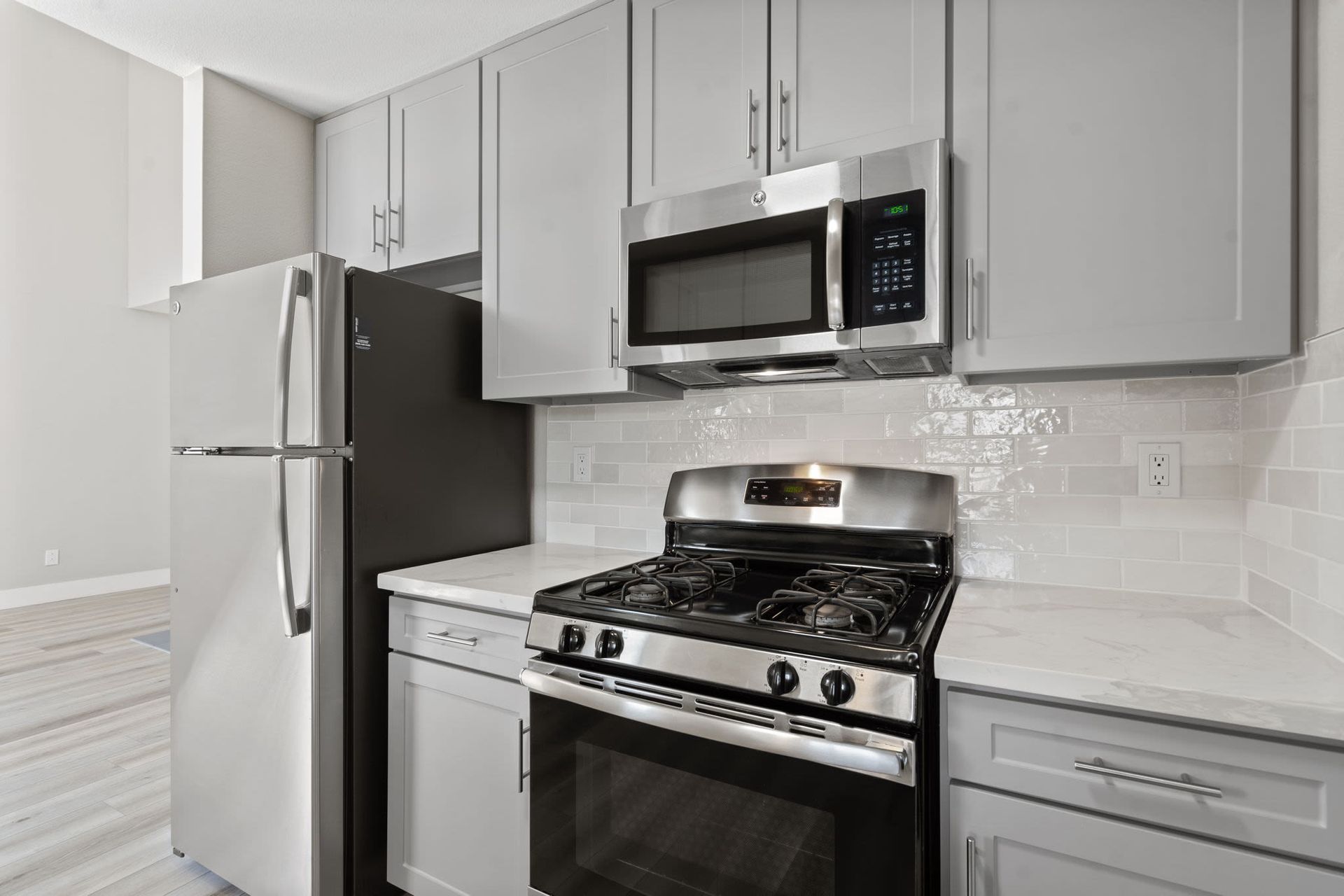 Modern kitchen with stainless-steel fridge, microwave, and gas range.