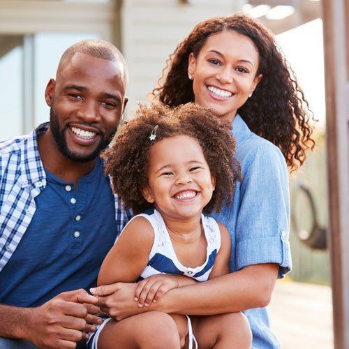 Young black family embracing outdoors and smiling at camera