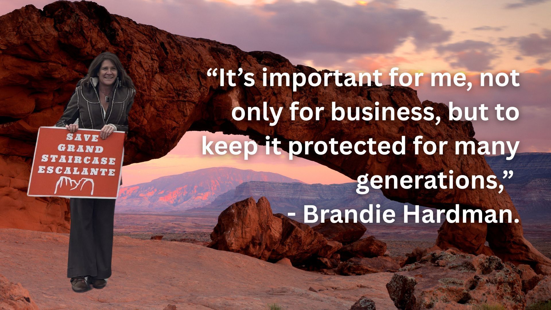Red rock arch with canyons and sunset in the distance and with person holding a sign that says 