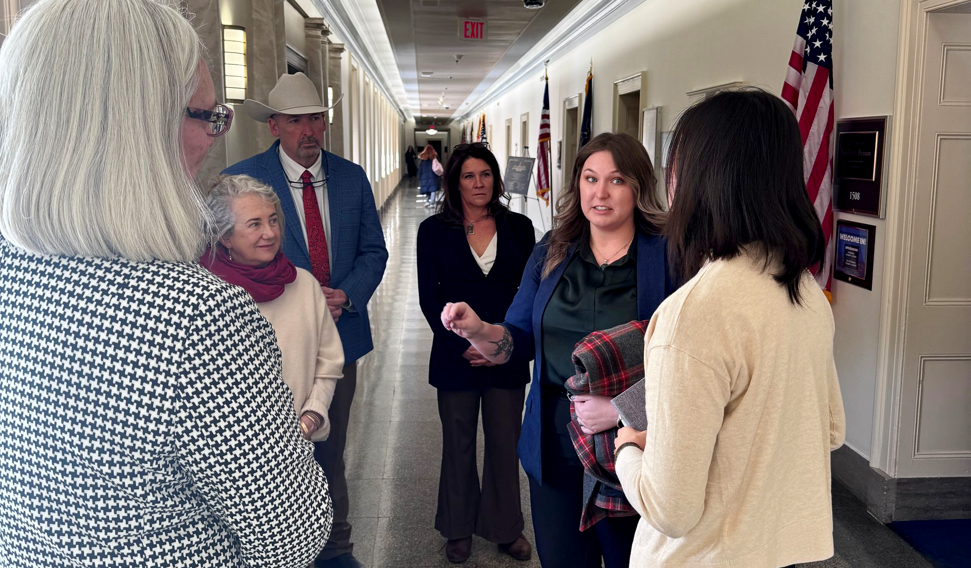 Group of people speaking to a Congressional staff member in a hallway