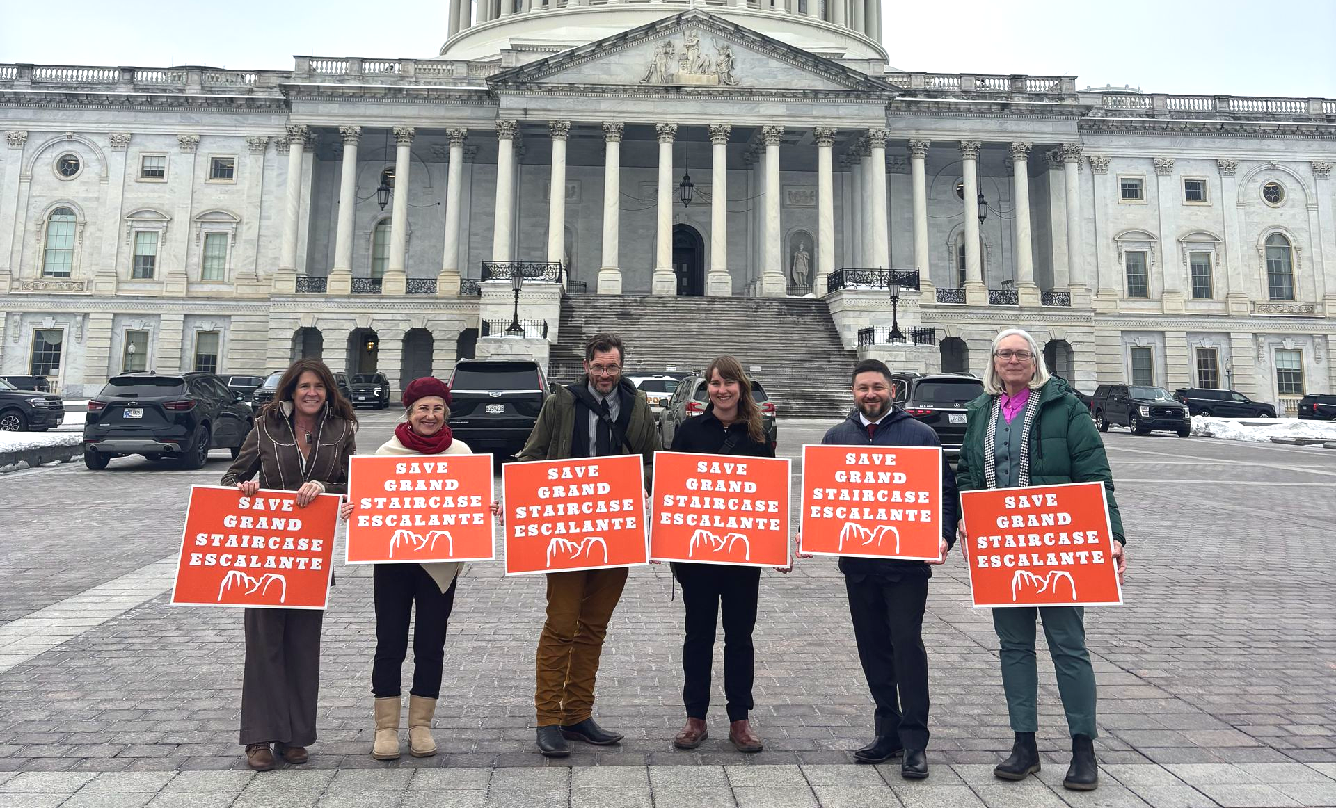 Group of people in front of Capitol building with signs that say 