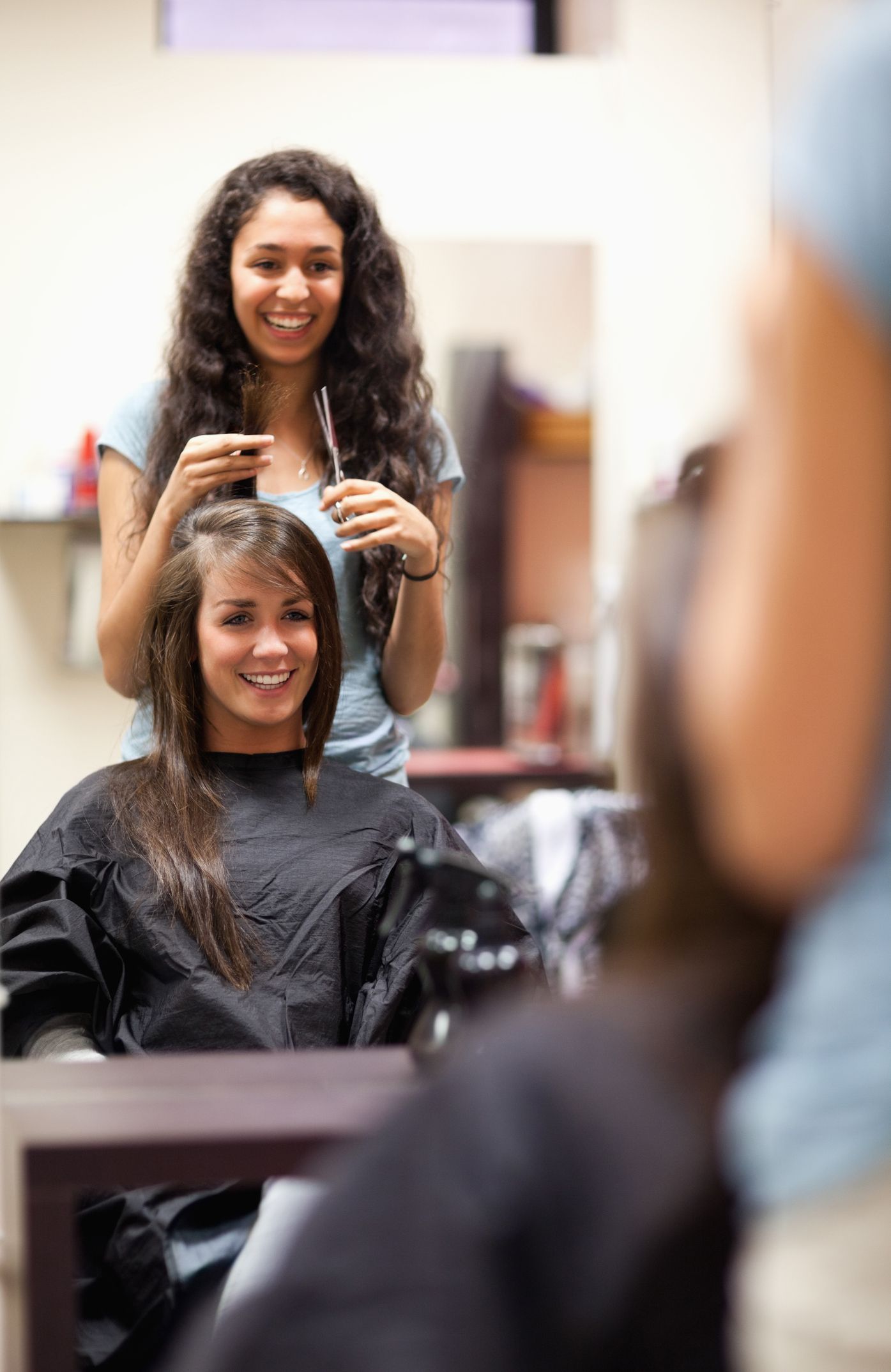 Hair salon services are provided by a stylist who cuts a woman's hair.