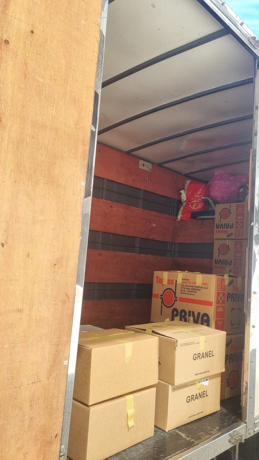 Dentro de un camión lleno de cajas de cartón, algunas etiquetadas como “PRIVA” y “Toscana”.