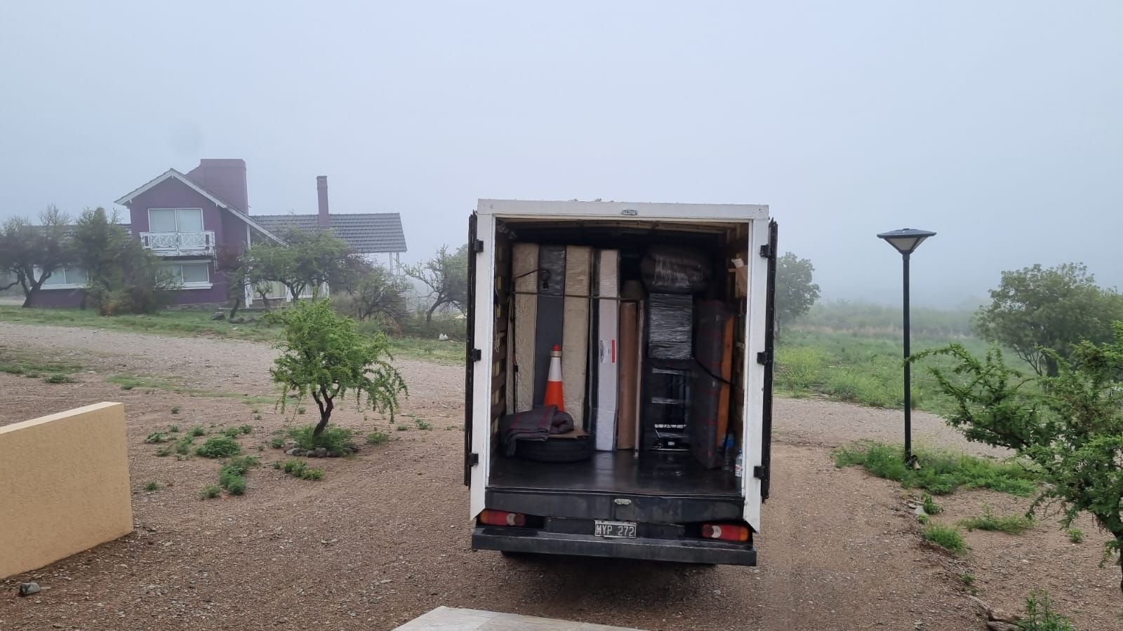 Un camión de mudanzas entró en una entrada cargado de muebles en un entorno exterior lleno de niebla.