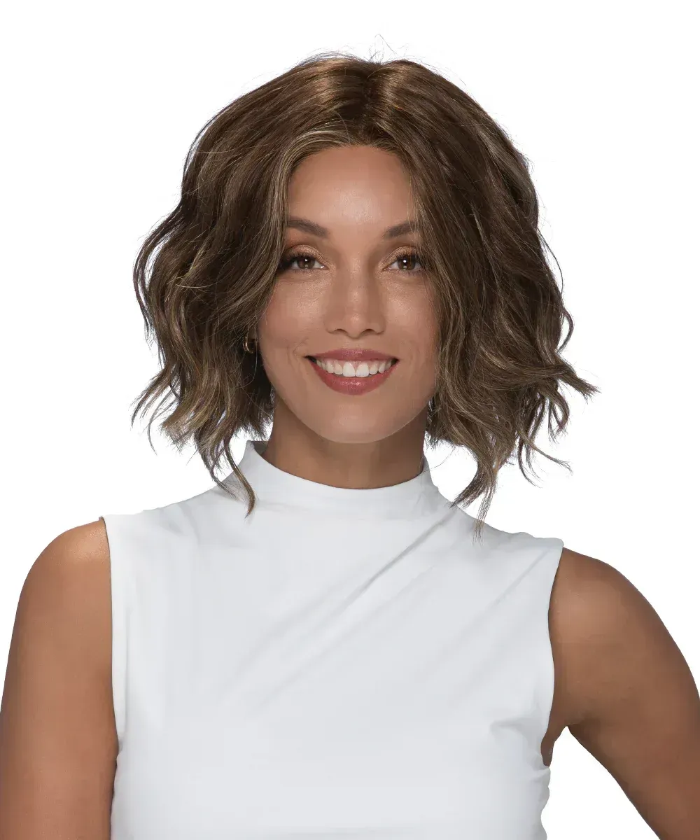 A woman wearing a wig and a white shirt is smiling.