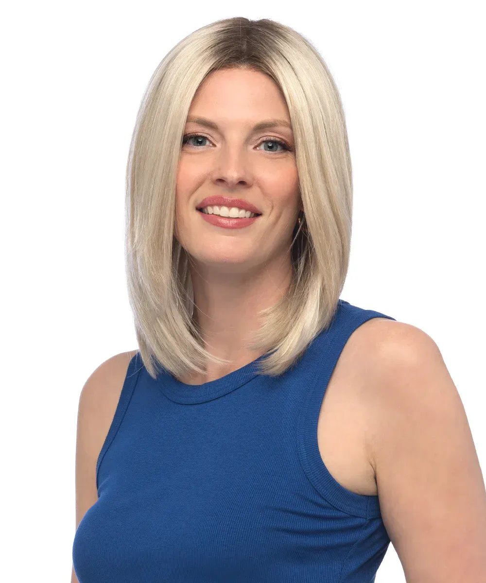 A woman wearing a blonde wig and a blue tank top is smiling.